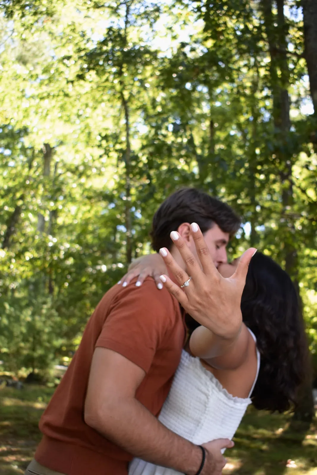 Emily showing her engagement ring as she kisses Thomas in the garden.