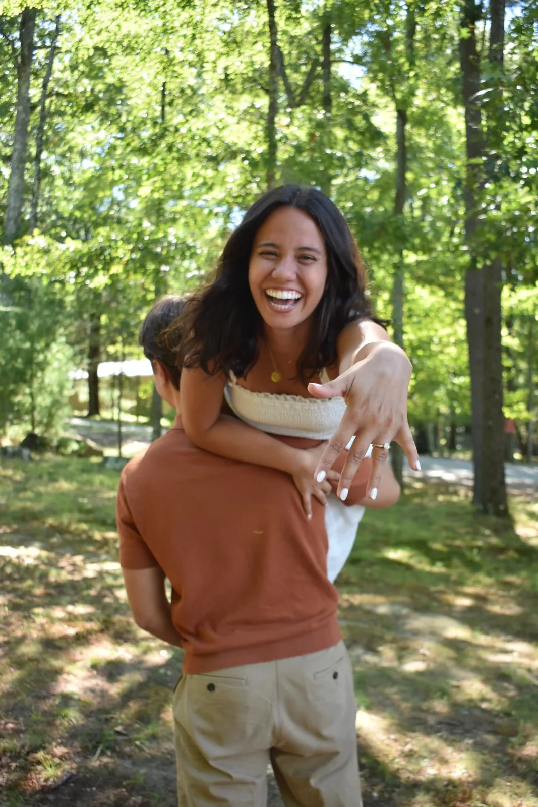 Emily laughing on Thomas’s back and showing her engagement ring.