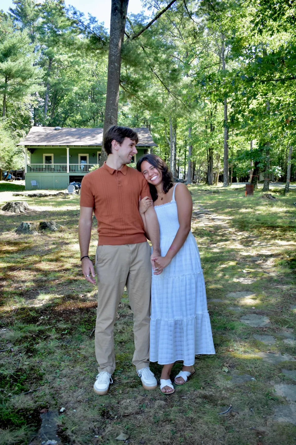 Emily and Thomas holding hands together beneath the trees.